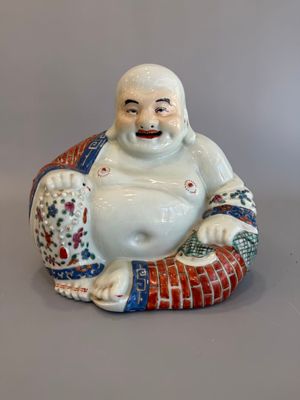 une figurine représentant un Bouddha riant, assis sur un coussin