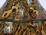 a brown and green vase sitting on a white table