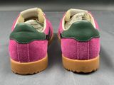 pink and green sued sneakers with gum soles on a gray surface