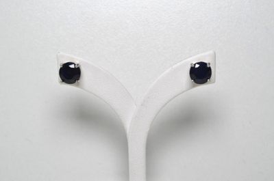 une paire de boucles d'oreilles à clous ornées de diamants noirs, présentées sur un socle blanc