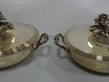 two silver plated dishes with handles and handles on a white surface