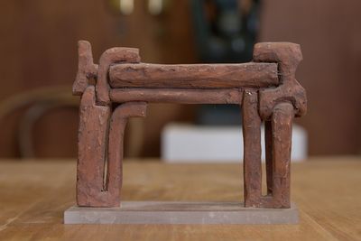 une petite structure en bois posée sur une table, avec un vase en arrière-plan
