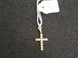 un collier avec une croix et une étiquette attachée à celle-ci, posé sur un fond noir