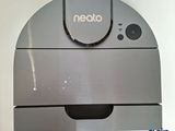 a close up of a neato vacuum cleaner on a white surface