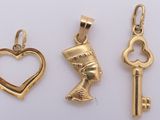 three gold charms with a heart, key, and an egyptian head