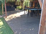 a wooden deck with a table and chairs under a pergol roof