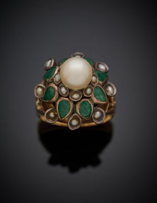 un gros plan d'une bague ornée d'une perle et d'une émeraude sur un fond noir