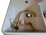 a white sink with a gold faucet and a gold faucet