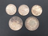 four silver coins of different sizes and shapes on a black surface