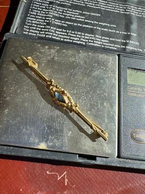 une broche en or posée sur une balance posée sur une table