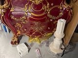 un lit rouge orné de motifs dorés, dans une chambre