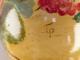 a yellow vase with red flowers painted on it