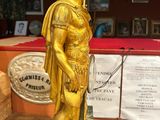 gold statue of a roman soldier on a marble base in a room