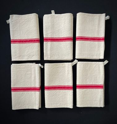 quatre serviettes blanches à rayures rouges sont posées sur une surface noire