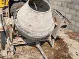 a cement mixer sitting next to a cement wall