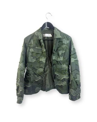 une veste de camouflage verte suspendue à un cintre sur un mur blanc
