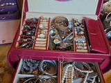 une valise rose remplie de nombreux bijoux, posée sur une table