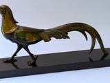 statue en bronze représentant un oiseau, posée sur un socle noir, sur fond blanc