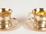 une paire de tasses et soucoupes plaquées argent posées sur un fond blanc