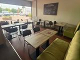 tables and chairs in a room with a large window and a green couch
