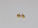 une paire de boucles d'oreilles en or en forme de cœur posées sur un fond blanc