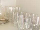 many glasses and a pitcher on a shelf in a room