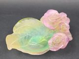 a pink and green glass flower on a green leaf