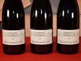 three bottles of wine are lined up on a red table