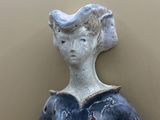 a ceramic sculpture of a woman holding a bowl