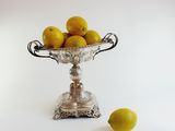 a silver bowl filled with lemons next to a lemon