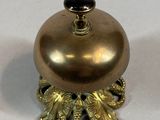 a small gold bell with a black knob on it