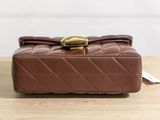brown quilted purse with gold buckle on wooden table