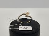 un gros plan d'une bague dans une boîte noire posée sur une surface blanche