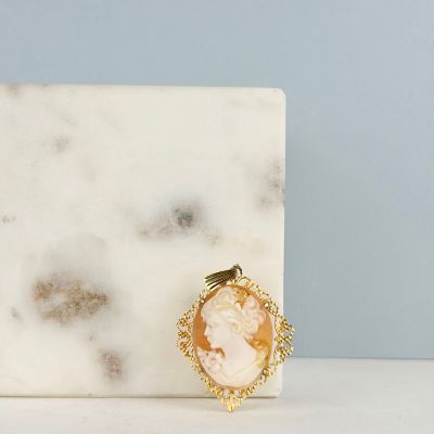 un gros plan sur une dalle de marbre blanc sur laquelle repose une broche en or