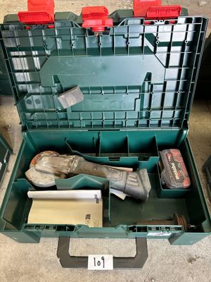 une boîte à outils verte posée par terre, contenant des outils