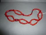 an image of a necklace made of red coral beads on a gray surface