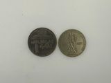 two coins that are sitting side by side on a white surface