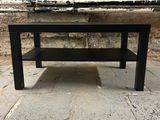 a black table with a shelf on it on a stone floor