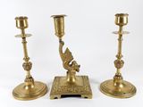 three brass candlesticks with a bird on top of them