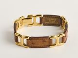 une photo d'un bracelet doré et marron muni d'une étiquette