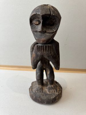 an old wooden statue of a man holding a comb in his hands