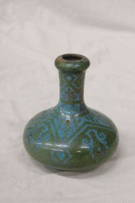 un petit vase vert posé sur une surface blanche