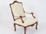 a white chair with a wooden frame and a beige upholstered seat