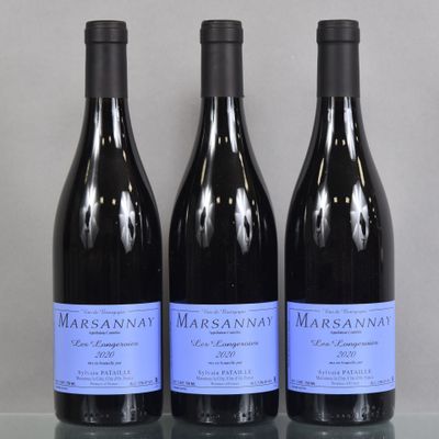 three bottles of wine are lined up on a glass table