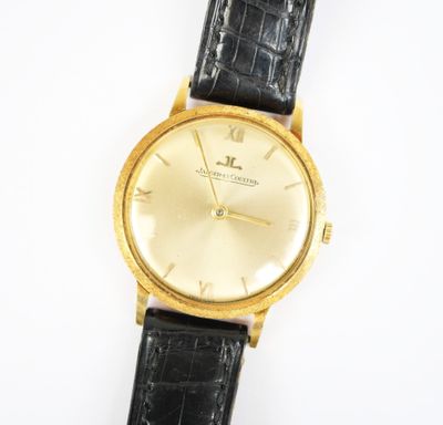 un gros plan d'une montre en or avec un bracelet en cuir noir