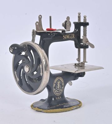 une machine à coudre noire et argentée posée sur un support blanc