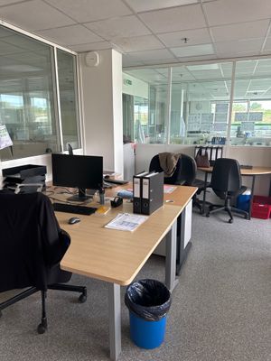 un bureau avec deux ordinateurs et une poubelle dans un coin