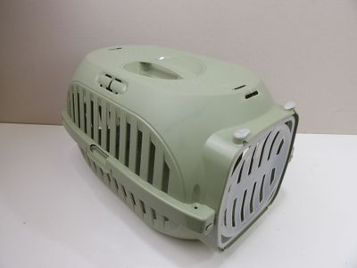 une petite cage de transport verte posée sur une table blanche