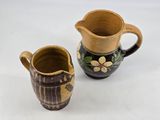 pair of brown and black ceramic jugs with flowers on them