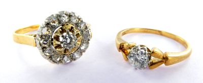 two gold rings with diamonds on them on a white surface